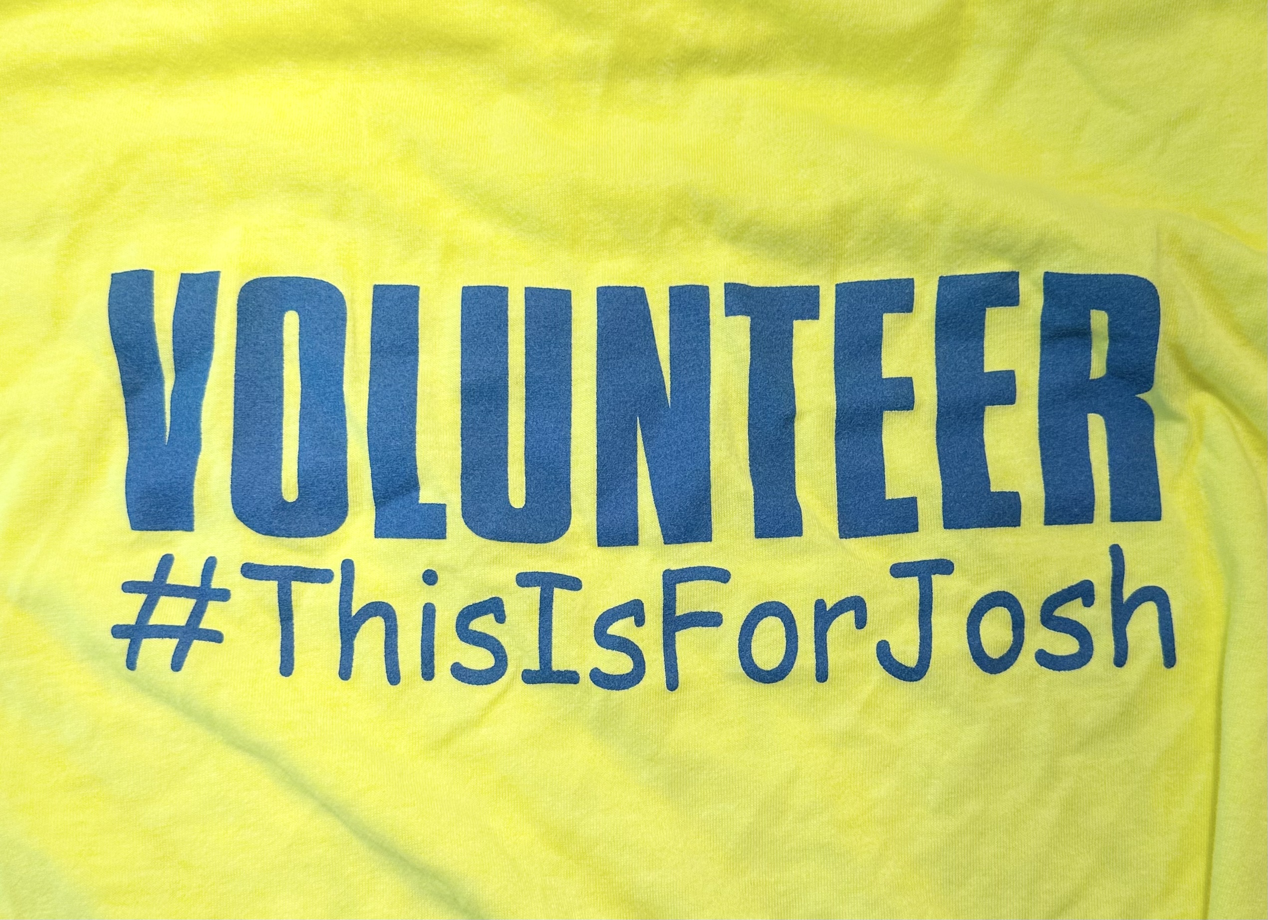 Yellow fabric background with the words "Volunteer" and "#ThisIsForJosh" in blue.